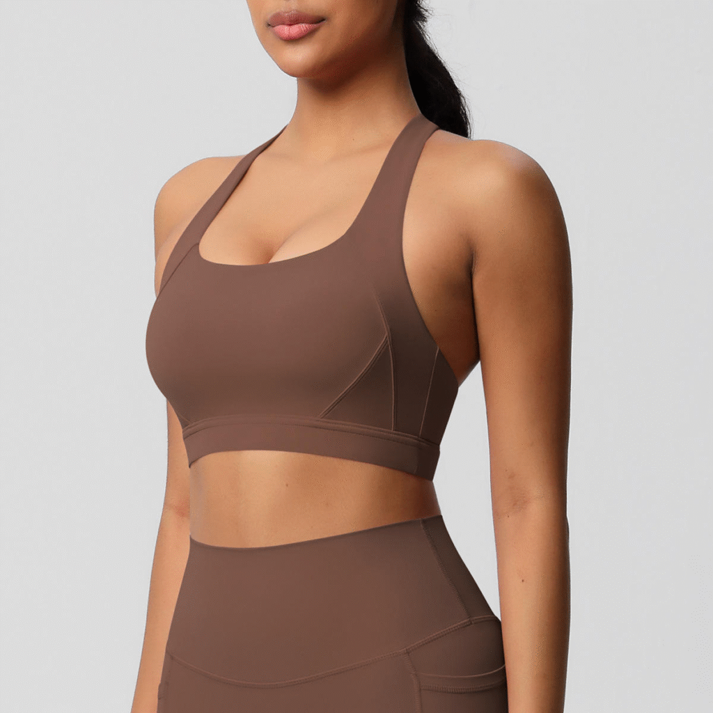 Woman wearing brown racerback sports bra with wide straps and contour stitching, paired with matching high-waisted leggings.