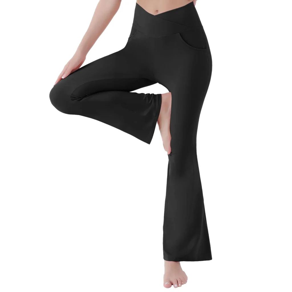 Woman wearing black crossover high-waisted flare leggings in a yoga pose, barefoot against white background.
