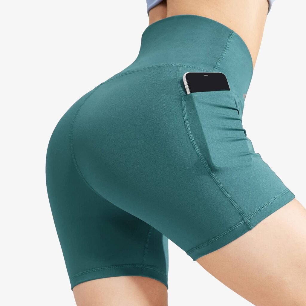 Close-up of teal high-waisted biker shorts with side pocket holding a smartphone, worn by a woman.
