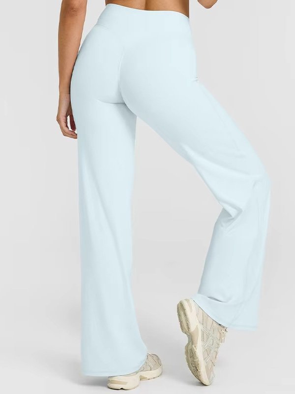 A pair of high-waisted, wide-leg custom yoga pants in light blue, highlighting the comfortable fit and flowy design, worn by a model in beige sneakers, showcasing flexibility and style