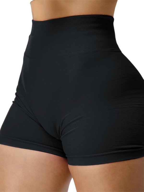 Close-up of a woman wearing high-waisted black athletic shorts, highlighting the smooth, stretchy fabric and fitted design around the waist and hips