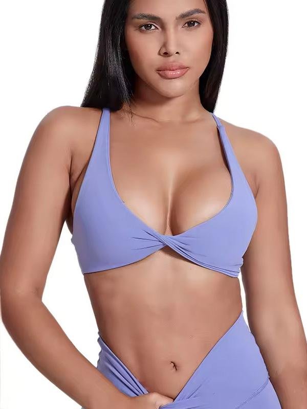 Woman wearing a lavender wrap-style sports bra with thin straps, showcasing a flattering twist design at the front.