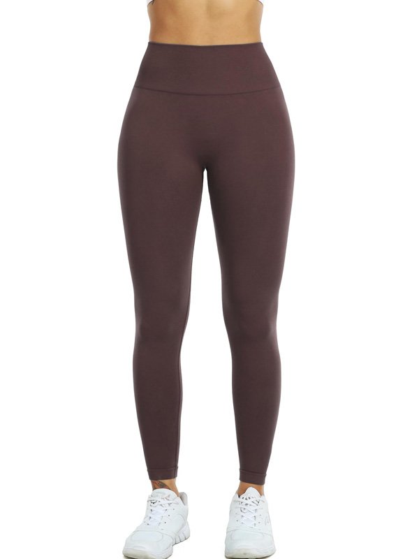 A front view of a woman wearing high-waisted, full-length brown leggings paired with white sneakers. The leggings have a smooth, fitted design suitable for activewear or casual wear.