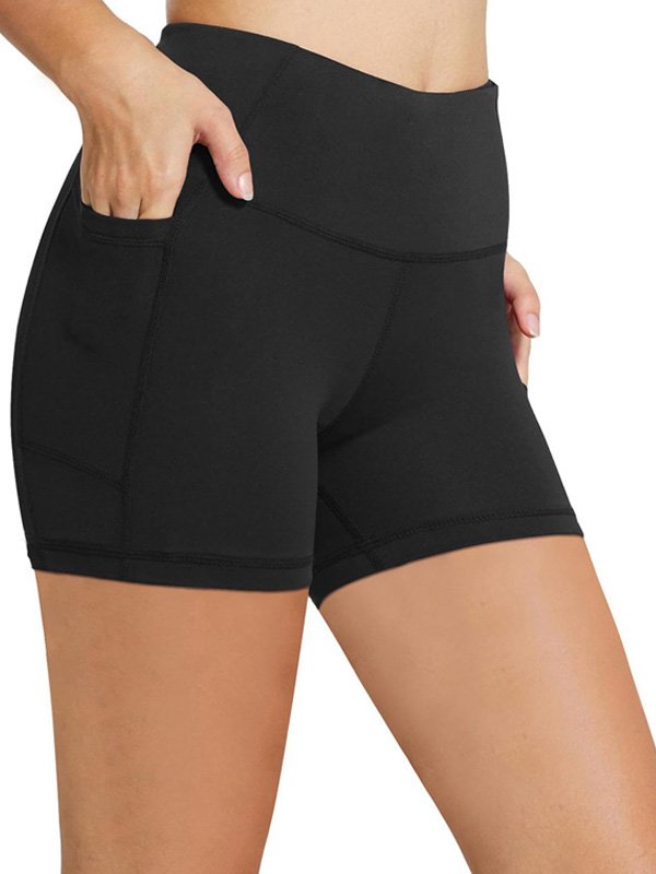 Woman wearing high-waisted black athletic shorts with side pockets, showcasing a sleek, comfortable fit and functional design