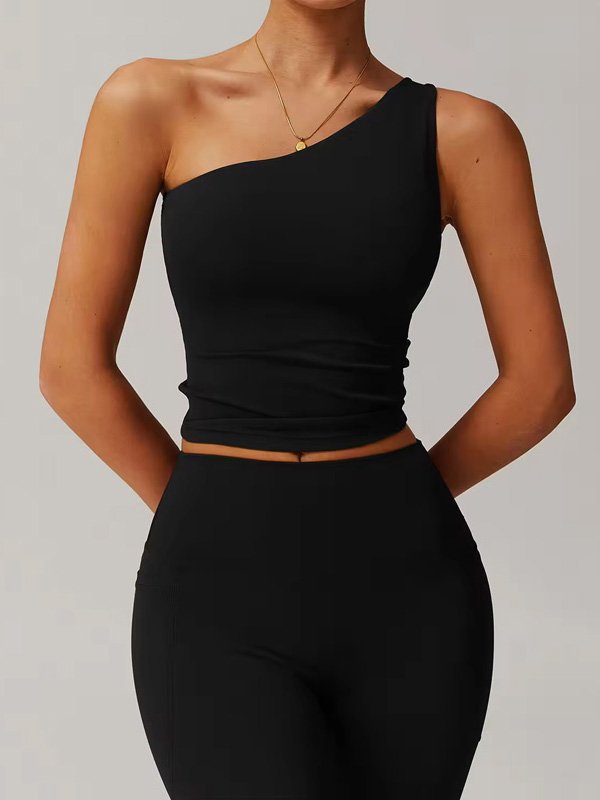 A woman wearing a black one-shoulder sports top, paired with matching leggings, showcasing the sleek, minimal design of the activewear