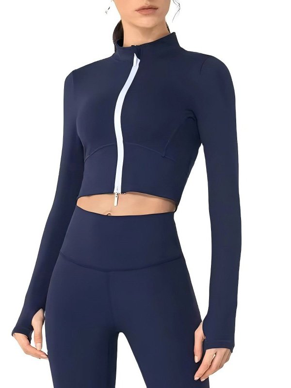 A woman wearing a navy blue zip-up crop jacket with a white zipper, paired with matching leggings, showcasing a sleek and modern athleisure look.