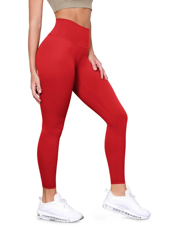 A pair of high-waisted custom yoga pants in red, showcasing a sleek fit and smooth fabric, displayed on a model wearing a beige crop top and white sneakers, highlighting the design and comfort of the pants
