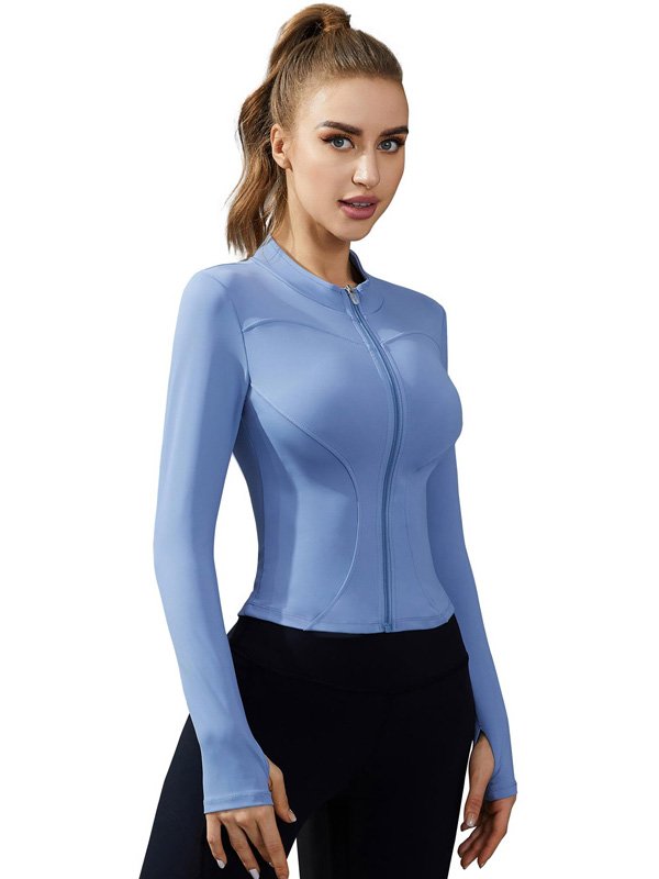 A woman wearing a light blue zip-up athletic jacket with long sleeves, paired with black leggings, showcasing a fitted and stylish activewear look.