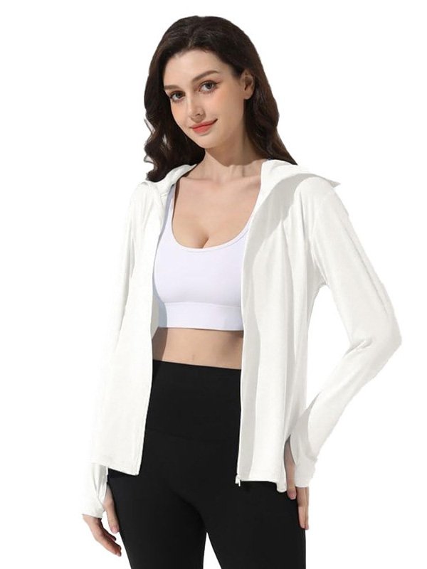 A woman wearing a white zip-up hoodie with a hood, paired with a white sports bra and black leggings, showcasing a fresh, comfortable athleisure look