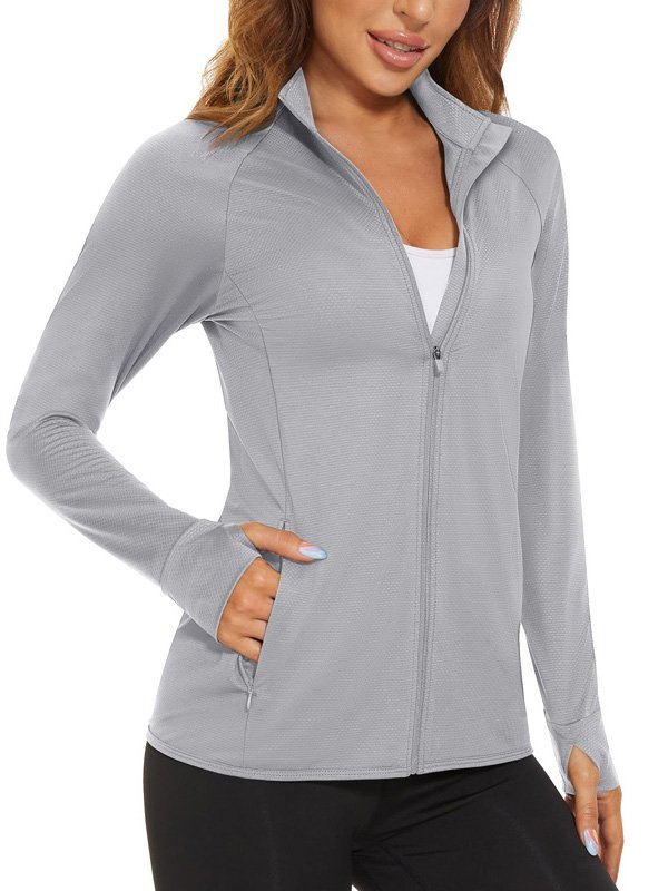 A woman wearing a light grey zip-up jacket over a white sports bra, paired with black leggings, showcasing a comfortable and versatile athleisure look.