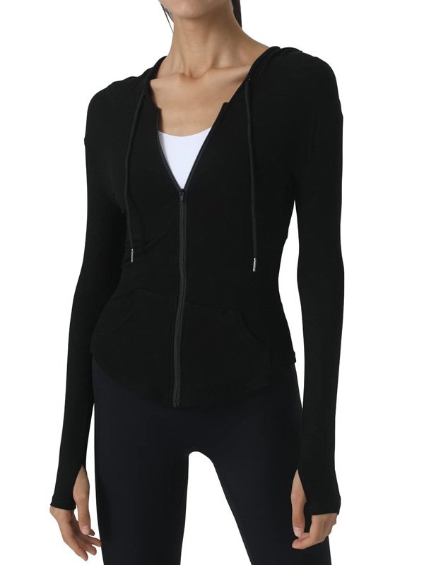 A woman wearing a black zip-up hoodie with a hood, paired with black leggings, showcasing a sleek and minimalist athleisure look.