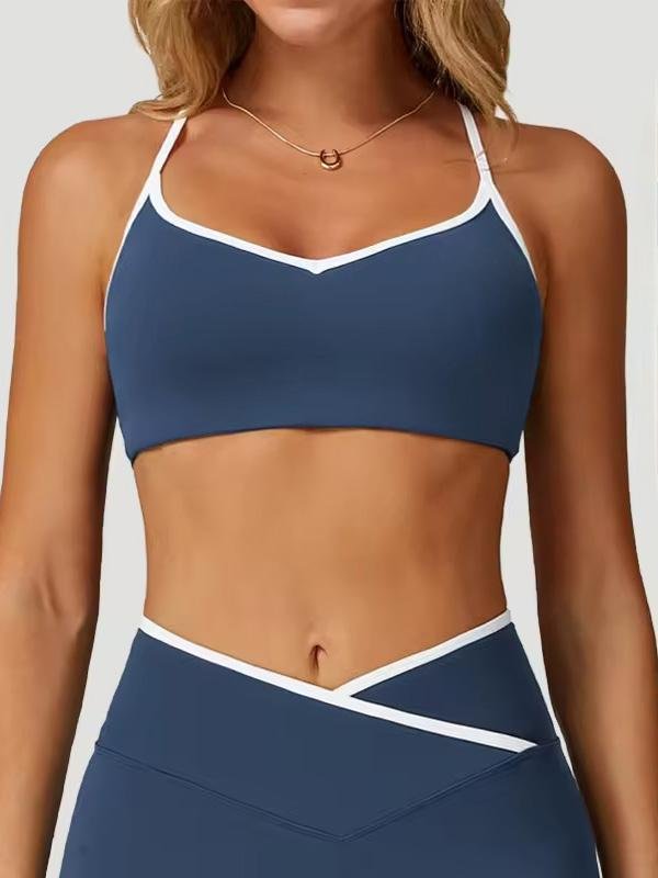 A woman wearing a navy blue sports bra with white trim, featuring a simple yet stylish design, paired with matching leggings.