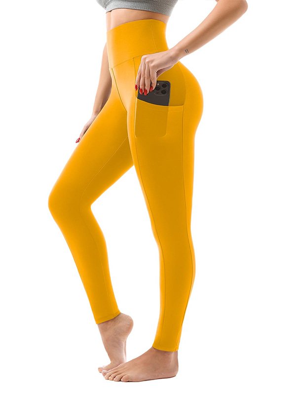 A side view of a woman wearing high-waisted yellow leggings with a side pocket, holding a smartphone. The leggings have a sleek, snug fit and are styled barefoot, ideal for activewear or casual wear.