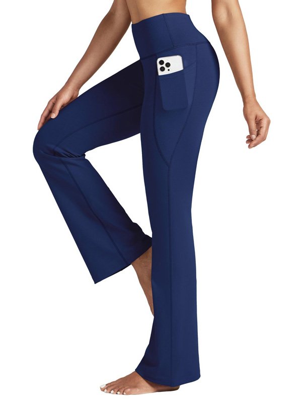 A pair of high-waisted flared yoga pants in navy, featuring a side pocket with a phone, worn by a model barefoot, highlighting comfort, style, and functionality