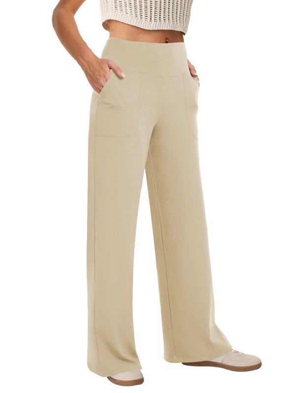 A pair of wide-leg custom yoga pants in beige, featuring a high waistband and side pockets, worn by a model with beige sneakers, highlighting comfort and versatility