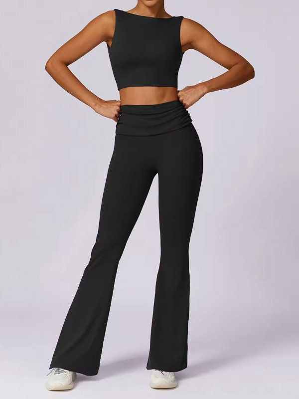 A front view of a woman wearing a black sleeveless crop top and matching high-waisted flared leggings, paired with white sneakers. The outfit showcases a sleek, fitted design ideal for active or casual wear.