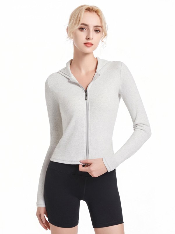A woman wearing a light grey zip-up hoodie, paired with black high-waisted shorts, showcasing a casual and comfortable athleisure look.