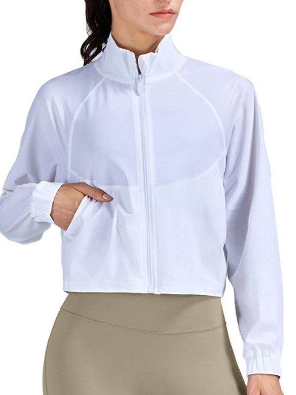 A woman wearing a white zip-up jacket with a high collar and elastic cuffs, paired with beige leggings, showcasing a sleek and sporty athleisure look