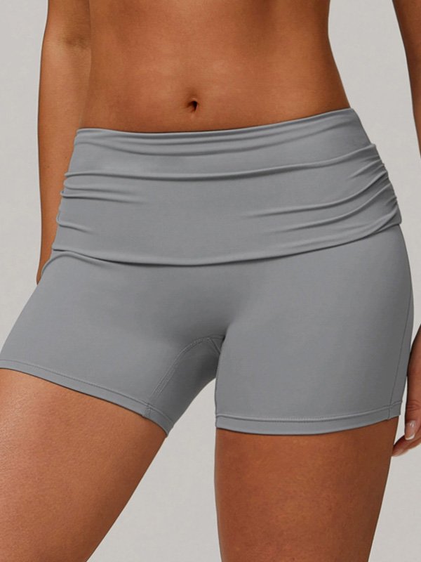 Woman wearing high-waisted gray athletic shorts with a ruched waistband, showcasing a smooth, fitted design and comfortable stretch.
