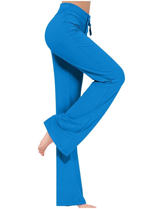 A pair of wide-leg custom yoga pants in bright blue with a drawstring waistband, worn by a model barefoot, showcasing flexibility and comfort in a relaxed fit.